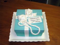 a blue box with pearls and a white ribbon on it sitting on top of a wooden table