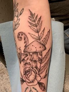 a black and white tattoo on the leg of a woman's arm with flowers