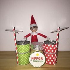 an elf is sitting on top of buckets with two drums in front of him