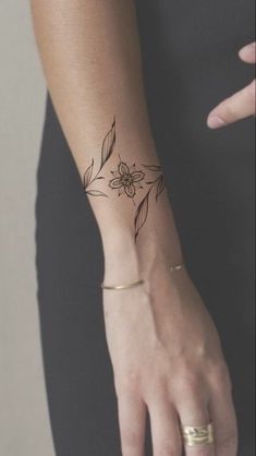 a woman's hand with a flower tattoo on her left wrist and the other arm