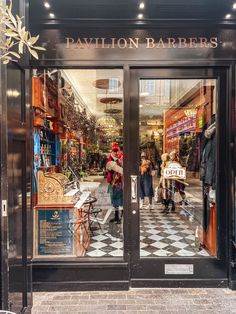 people are walking in and out of the entrance to a store with glass doors that say pavilion barbers