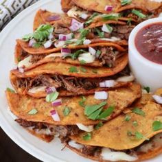 a white plate topped with lots of tacos and sauce