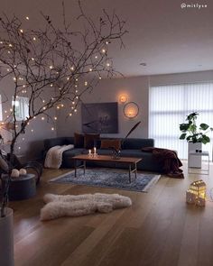 a living room filled with furniture and lights on the wall next to a tree in front of a window