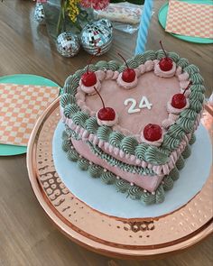 a heart - shaped cake with cherries on it sitting on top of a table