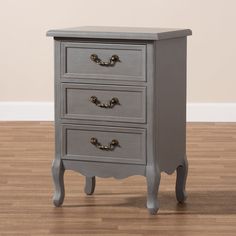 a small grey chest of drawers on a wooden floor