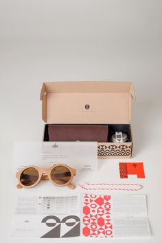 an open box with sunglasses and papers on the table next to it is a pair of glasses