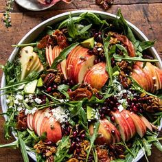 an apple salad with spinach, pecans and cranberries in a bowl