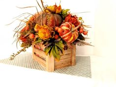 a wooden box filled with lots of different types of fall flowers and pumpkins on top of a checkered table cloth