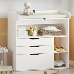 a baby changing table with three drawers and a teddy bear on top in a room