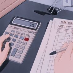 a person using a calculator on top of a desk next to a pen and paper