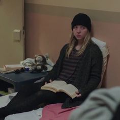 a woman sitting on a bed reading a book