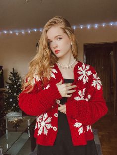 a woman standing in front of a christmas tree wearing a red and white knitted sweater