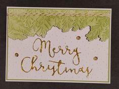 a merry christmas card with gold foil lettering and green leaves on the bottom, in front of a black background