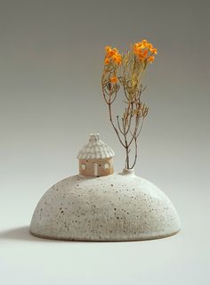 there is a vase with flowers on top of the base and a house in the middle