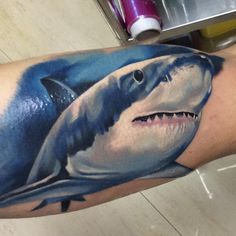 a man's arm with a shark tattoo on it and his face painted in blue