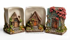 three ceramic figurines with houses and flowers on them