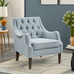 a blue chair sitting in a living room next to a table with vases on it