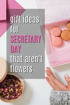 a pink box with flowers and cookies in it on top of a white table next to a