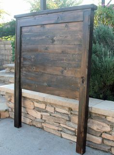 a wooden sign sitting next to a stone wall