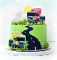 a green cake with two trucks on the top and one truck on the bottom, in front of a sky background