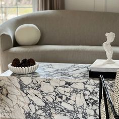 a marble coffee table in the middle of a living room with two vases on it