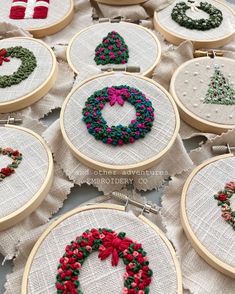 some cross stitch christmas wreaths are on the table