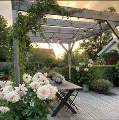 a wooden deck with flowers and potted plants in the foreground, at sunset