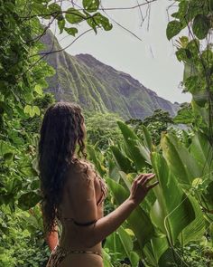 a woman standing in the jungle looking at her cell phone