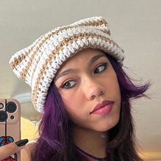 a woman with purple hair is taking a selfie while wearing a knitted hat