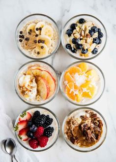 four bowls filled with different types of food on top of a white counter next to utensils