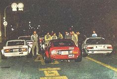 several police officers standing next to their cars on the side of the road at night