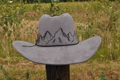 Mountain scene meticulously crafted and hand- burned into this adjustable cowboy hat. This versatile design can be purchased as is, or tailored to your taste with personalized touches. Imagine adding intricate artwork or a layered hat band adorned with flowers, feathers, or stones of your choosing. Our customization process is an artistic journey, with designs drawn freehand, ensuring each hat is a one of a kind unique masterpiece. Prices for additional customization vary depending on the complexity and detail of your desired addition. Upon placing your order, we'll promptly provide you with a quote and commence artwork creation upon receipt of payment. Please note, due to the bespoke nature of customization and our commitment to hygiene standards, this product is non-refundable. Turnaroun Fitted Outdoor Cap, Rustic Outdoor Hat, Adjustable Gray Hat For Rodeo, Handmade Country Hat For Outdoor, Fitted Country Hats For Outdoor, Fitted Hats With Curved Brim For Outdoor, Fitted Outdoor Hats With Short Brim, Fitted Outdoor Hat With Curved Brim, Fitted Outdoor Hat With Short Brim