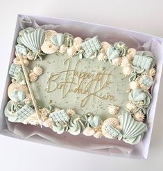 a birthday cake decorated with seashells and the words happy birthday written on it