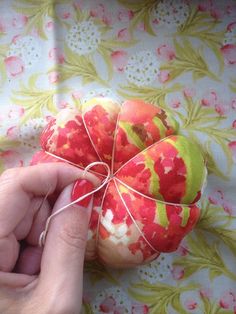 someone is sewing on an ornament with red flowers