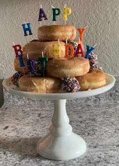 a birthday cake with donuts and sprinkles on a white platter