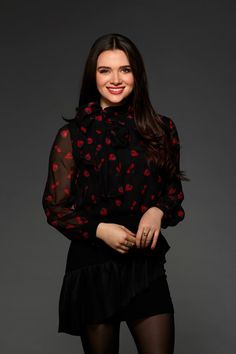 a woman in black and red is posing for the camera with her hands on her hips