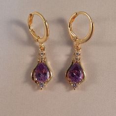 These Beautiful Purple Pear Shape Zircon Earrings Are Made Of 18k Yellow Gold Filled With (Lab Created) Purple And White Topaz Zircon Stones.Brand New And Never Been Worn. Lead And Nickel Free. These Fine Quality Earrings Are Perfect For Special Occasions, Or A Special Gift. Get An $18 Gift Of Your Choice In My Listings With Purchase Of Two Or More Items. Please Send Offers And Questions. Stone :6 X 8mm Or .24" X .31" Earrings: 31 X 9mm Or 1.22" X .35" Hoop Dia: .43" Hoop Clasp (Pierced) Purple Gem Jewelry, Purple Sapphire Earrings, Gold And Purple Earrings, Gold Purple Jewelry, Purple Stud Earrings, Purple And Gold Earrings, Amethyst Teardrop Crystal Earrings, Elegant Gold Amethyst Crystal Earrings, Elegant Purple Teardrop Crystal Earrings