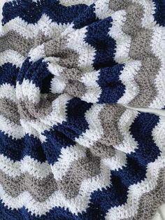 a crocheted blanket laying on top of a white table next to a pair of scissors