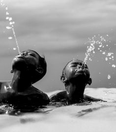 two children are playing in the water with their heads above the water's surface