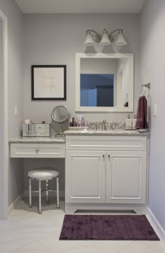 a bathroom with a vanity, mirror and stool in the corner on the floor next to the sink