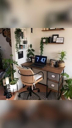 a desk with a laptop on top of it in a room filled with potted plants