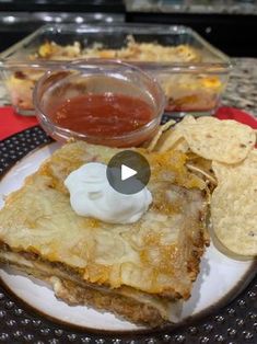 a white plate topped with food next to a bowl of sauce and tortilla chips