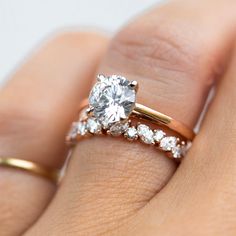 a woman's hand holding a gold ring with a diamond on top and two diamonds on the bottom