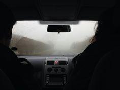 two people sitting in the passenger seat of a car on a foggy day,