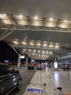 an airport terminal with cars and people walking around