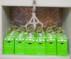 small green bags with faces on them are lined up in front of the eiffel tower