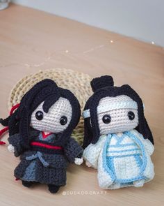 two crocheted dolls sitting next to each other on top of a wooden table