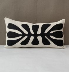 a black and white decorative pillow sitting on top of a bed next to a wall