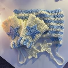 two crocheted hats with stars on them sitting on a table next to a candle