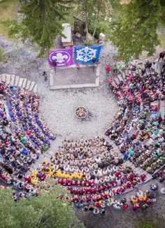 an aerial view of a large group of people sitting in front of a stage with a flag on it